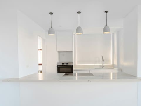 Built-In Ovens: minimalist white kitchen with pendant lights and integrated appliances