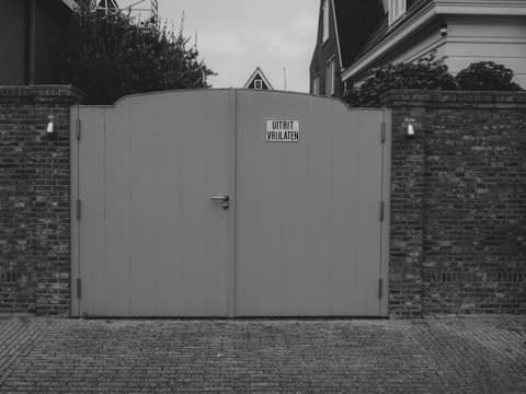 Gates & Security Grilles: a closed gray gate in a brick wall