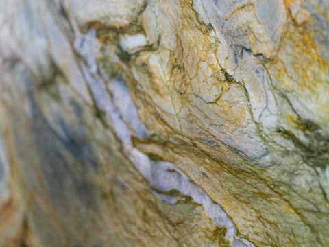A close-up of polished marble slab with white, gold, and green veining