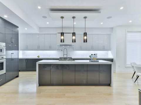 Kitchen Cabinets: a modern kitchen with grey cabinets, a white island, and three pendant lights