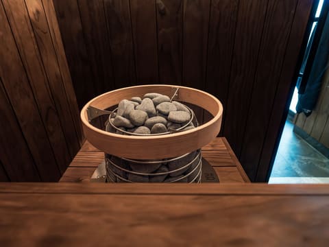 Steam Rooms & Saunas: traditional sauna heater with rocks in a wooden interior